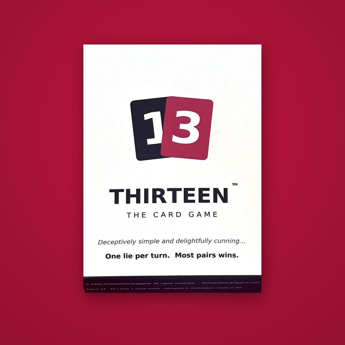 Front of the THIRTEEN card game box with the split 1 and 3 logo, on a crimson background